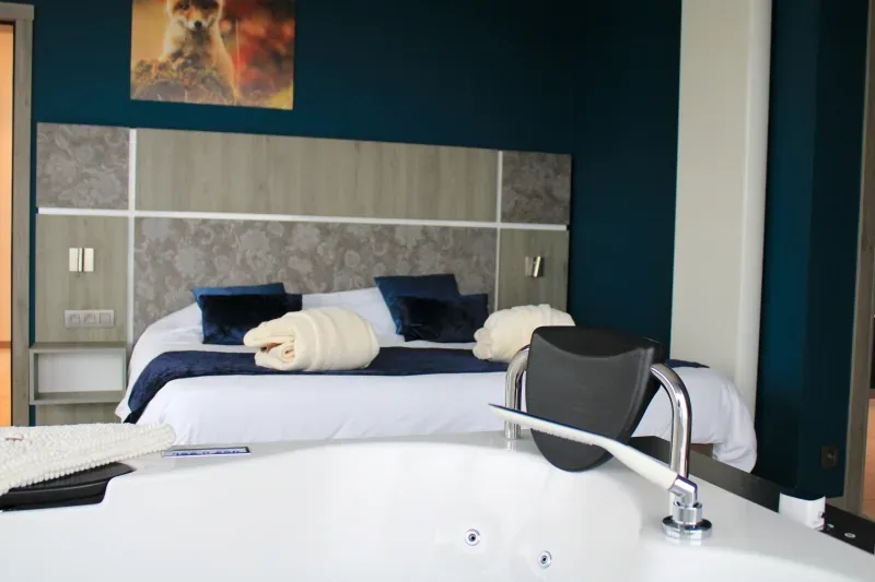 A premium bedroom with towels folded on the bed and the jacuzzi alongside it